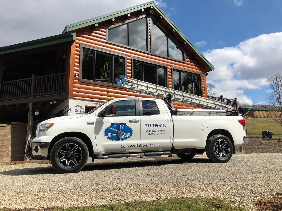 White pickup truck parked in front of an orange log cabin with a clear sky background